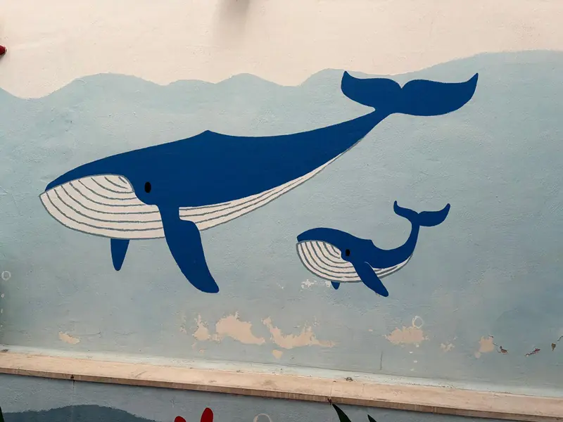 Una ballena y su cría pintadas en la pared del patio de la escuela