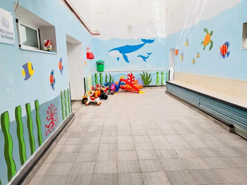 Patio de la escuela, con el fondo del mar pintado en las paredes y los correpasillos de los peques